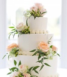 Wedding Cake with Peach Roses
Photography: Cassi Claire Photography
Read More:
http://www.insideweddings.com/weddings/casually-chic-country-club-wedding-in-new-york-with-pastel-details/662/ Three layer white wedding cake with pastel orange roses, green hydrangea sprigs, and greenery