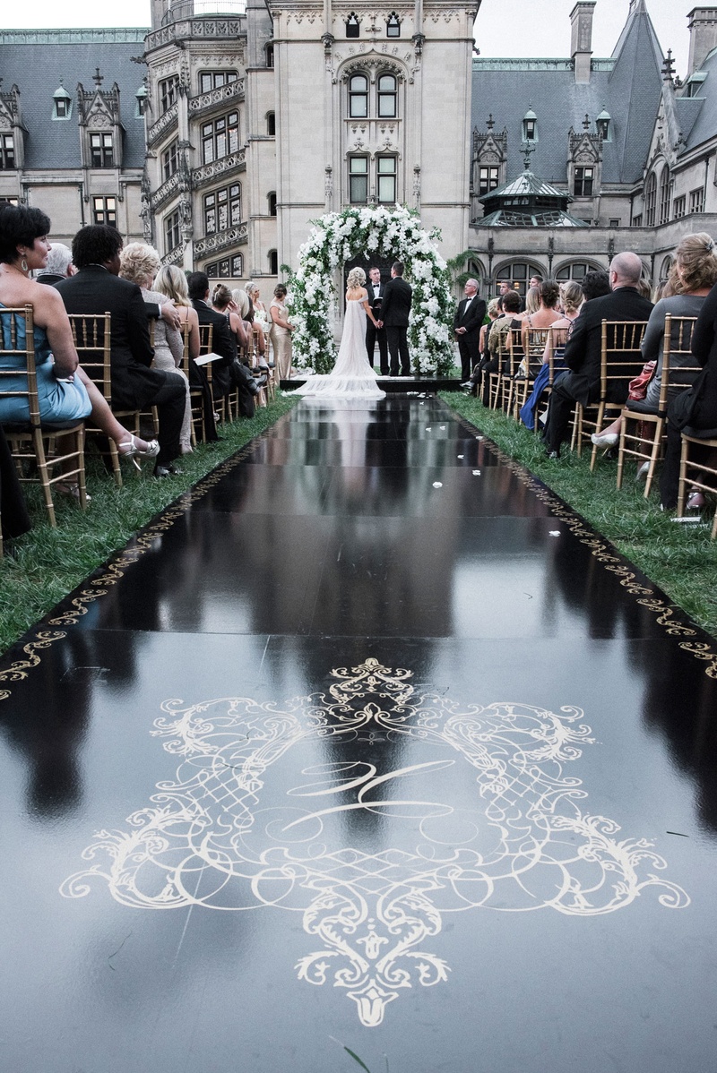 Black Aisle Runner with Custom Crest
Photography: Parker J Pfister Photographer
Read More:
http://www.insideweddings.com/weddings/gorgeous-alfresco-ceremony-tented-reception-at-a-luxurious-estate/1044/ Wedding ceremony aisle black runner with gold monogram crest and border grass lawn asheville nc