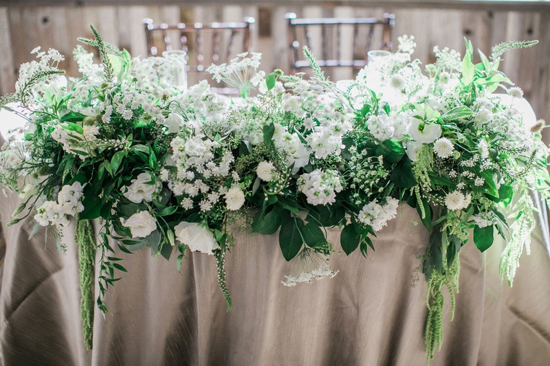 Lush Arrangement on Sweetheart Table
Photography: This Modern Romance
Read More:
http://www.insideweddings.com/weddings/rustic-chic-wedding-with-wooden-accents-and-verdant-details/861/ sweetheart table with lots of greenery with white flowers