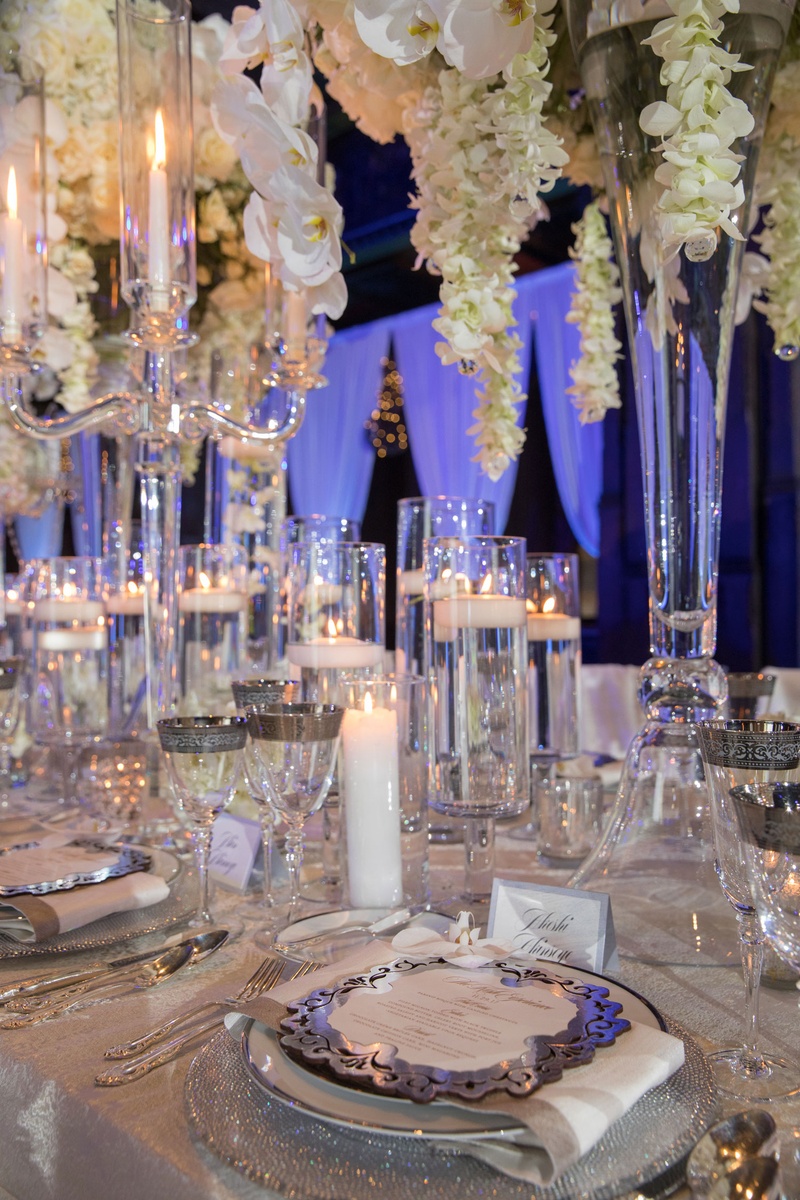 Flowers Falling Toward Place Setting
Photography: Collin Pierson Photography
Read More:
http://www.insideweddings.com/weddings/winter-wedding-inspirational-shoot-with-opulent-frosted-decor/1108/ Wedding reception tall centerpiece white orchids floating candles silver plates chargers