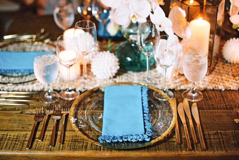 Gold-Rimmed Charger with Blue Napkin
Photography: Braedon Photography
Read More:
http://www.insideweddings.com/weddings/orthodox-jewish-wedding-with-outdoor-ceremony-inspired-by-the-sea/812/ Bare wood table with gold rim glass charger plate, gold flatware, white orchid flowers, candles