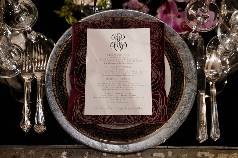 Menu with Dark, Laser-Cut Border
Photography: Bob %26 Dawn Davis Photography
Read More:
http://www.insideweddings.com/weddings/inspiring-styled-shoot-with-deep-dark-color-palette-in-chicago/1037/ wedding menu framed by dark laser-cut rose pattern on charger plate with black and grey marble rim
