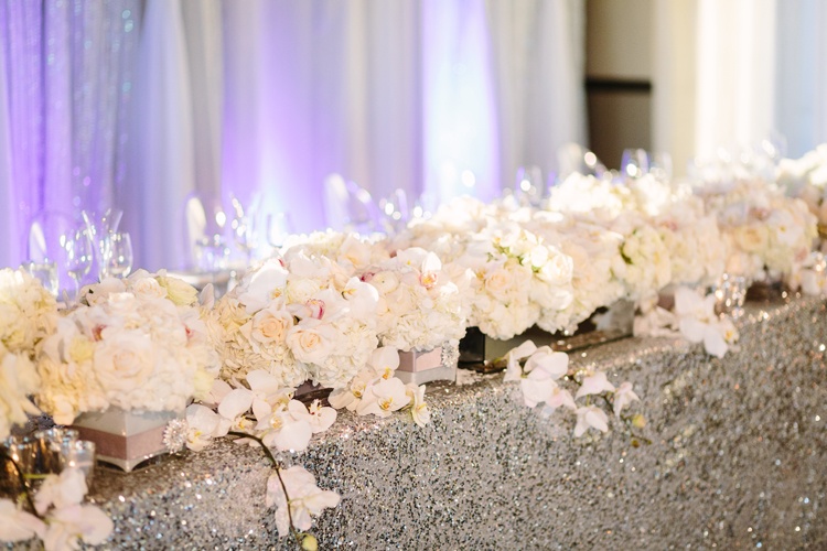 Orchids And Roses Line Head Table With Silver Sequin Cloth Flower Garland Runner Orchids And Roses Line Head Table With Silver Sequin Cloth Flower Garland Runner