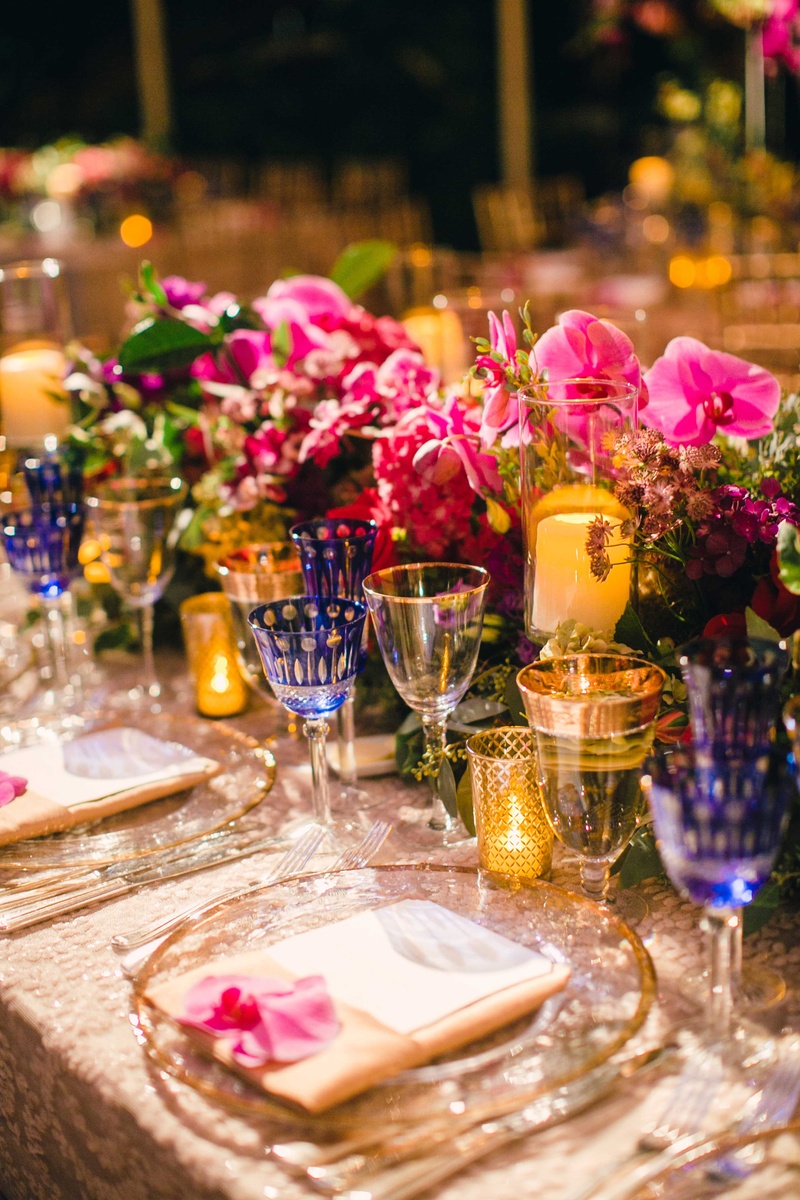 Candlelit Low Centerpiece with Blue Goblets
Photography: Mi Belle Photographers
Read More:
http://www.insideweddings.com/weddings/colorful-outdoor-wedding-with-supper-club-theme-in-los-angeles-ca/741/ Orchid bloom at wedding place setting with pink low flower table runner centerpiece