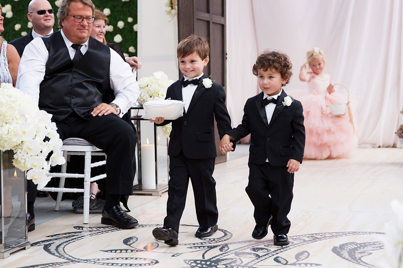 Cute Ring Bearers Holding Hands
Photography: Sarah Kate, Photographer
Read More:
http://www.insideweddings.com/weddings/outdoor-fall-ceremony-opulent-tented-reception-in-dallas-texas/1022/ Wedding ceremony wood aisle runner monogram two ring bearers tuxedos bow ties boutonnieres