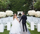 Bride and Groom Hold Hands in Front of Ceremony Site
