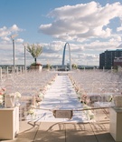 St. Louis Ceremony with a View
Photography: Switzerfilm
Read More:
http://www.insideweddings.com/weddings/rooftop-ceremony-with-city-views-dreamy-reception-in-st-louis/844/ Gateway Arch in background, white aisle runner lined with white and pink flowers, ghost chairs, sign