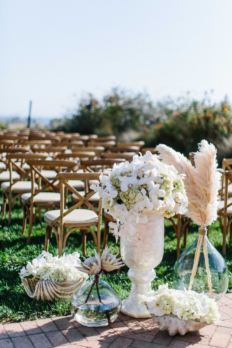 Botanicals in Glass Vessels
Photography: Braedon Photography
Read More:
http://www.insideweddings.com/weddings/orthodox-jewish-wedding-with-outdoor-ceremony-inspired-by-the-sea/812/ Wedding ceremony at Terranea with white orchid, hydrangea, protea, botanicals feathers in glass vase