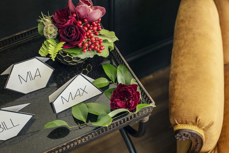 Geometric Escort Cards Photography: Kristina Lee Photography Read More: http://www.insideweddings.com/weddings/inspirational-wedding-shoot-with-black-red-white-geometric-decor/700/ Wedding reception place cards in geometric forms on table with greenery red roses, orchids