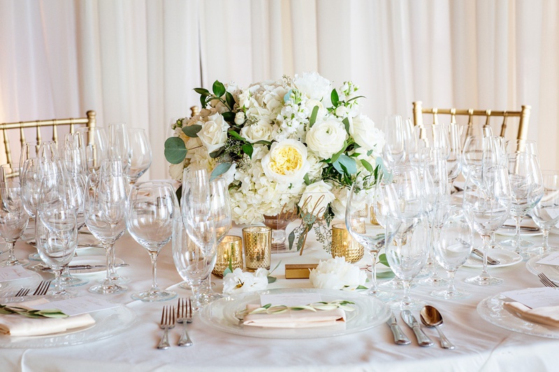 Soft, Low Centerpiece
Photography: Chard Photo
Read More:
http://www.insideweddings.com/weddings/alfresco-ceremony-on-the-coast-classic-ballroom-reception/1290/ small, low centerpiece with white flowers and eucalyptus leaves, surrounded by gold votive candles
