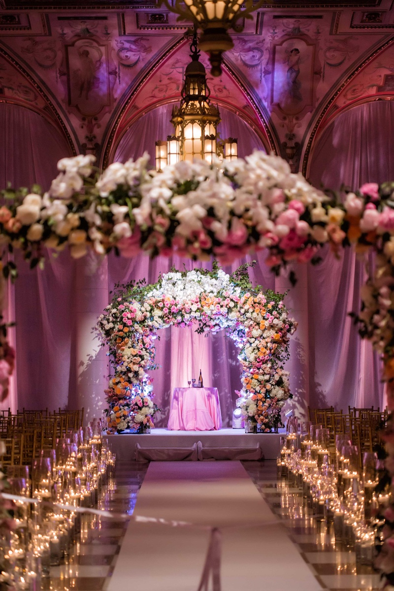 Flower Arches at Ballroom Ceremony
Photography: Muñoz Photography
Read More:
http://www.insideweddings.com/weddings/colorful-jewish-ceremony-ballroom-reception-at-the-breakers/818/ Gold and white checker floor candlelight lush pink orange white flower arch with chandelier