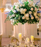Tall Centerpiece with Light Blue Flowers
Photography: K. Thompson Photography
Read More:
http://www.insideweddings.com/weddings/traditional-ceremony-ballroom-reception-with-blue-gold-decor/1201/ wedding reception centerpiece glass vase greenery white rose hydrangea blue flowers candles