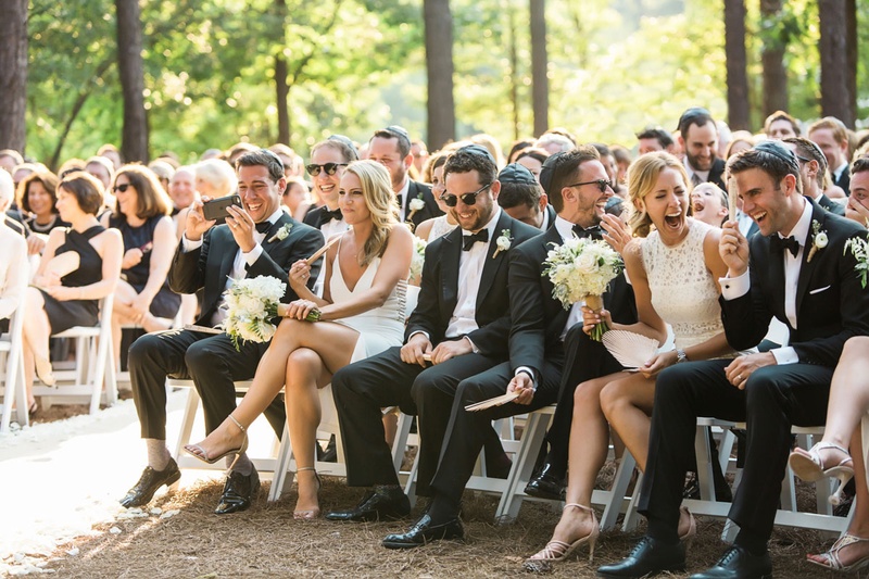 Expressive Friends %26 Family at Ceremony
Photography: Vue Photography
Read More:
http://www.insideweddings.com/weddings/summer-destination-wedding-with-rustic-elegant-decor-in-georgia/1032/ Bridesmaids and groomsmen sitting in front row white dresses outdoor wedding laughing guests smiling
