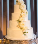 Five Tiers of Elegance
Photography: Vue Photography
Read More:
http://www.insideweddings.com/weddings/romantic-rustic-chic-wedding-at-a-whiskey-distillery-in-atlanta/942/ 5 tier cake with white frosting and white roses and green leaves curving down cake