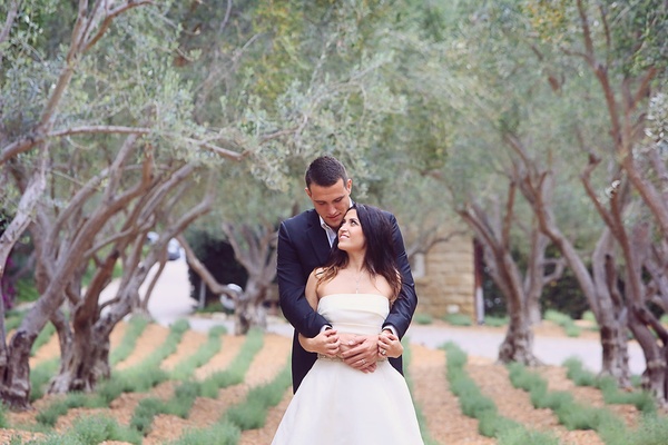 Bride In Monique Lhuillier Crop Top Wedding Dress Held By Groom In Armani Standing Under Trees Bride In Monique Lhuillier Crop Top Wedding Dress Held By Groom In Armani Standing Under Trees
