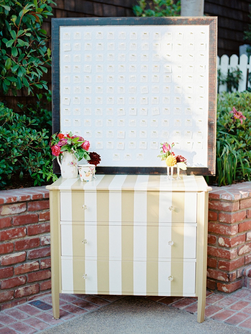 Gold %26 White Striped Escort Card Station
Photography: Ryan Ray Photography
Read More:
http://www.insideweddings.com/weddings/outdoor-wedding-with-vibrant-pink-orange-decor-in-california/723/ Gold and white stripe dresser with frame of escort cards pinned to board with gold bow pins