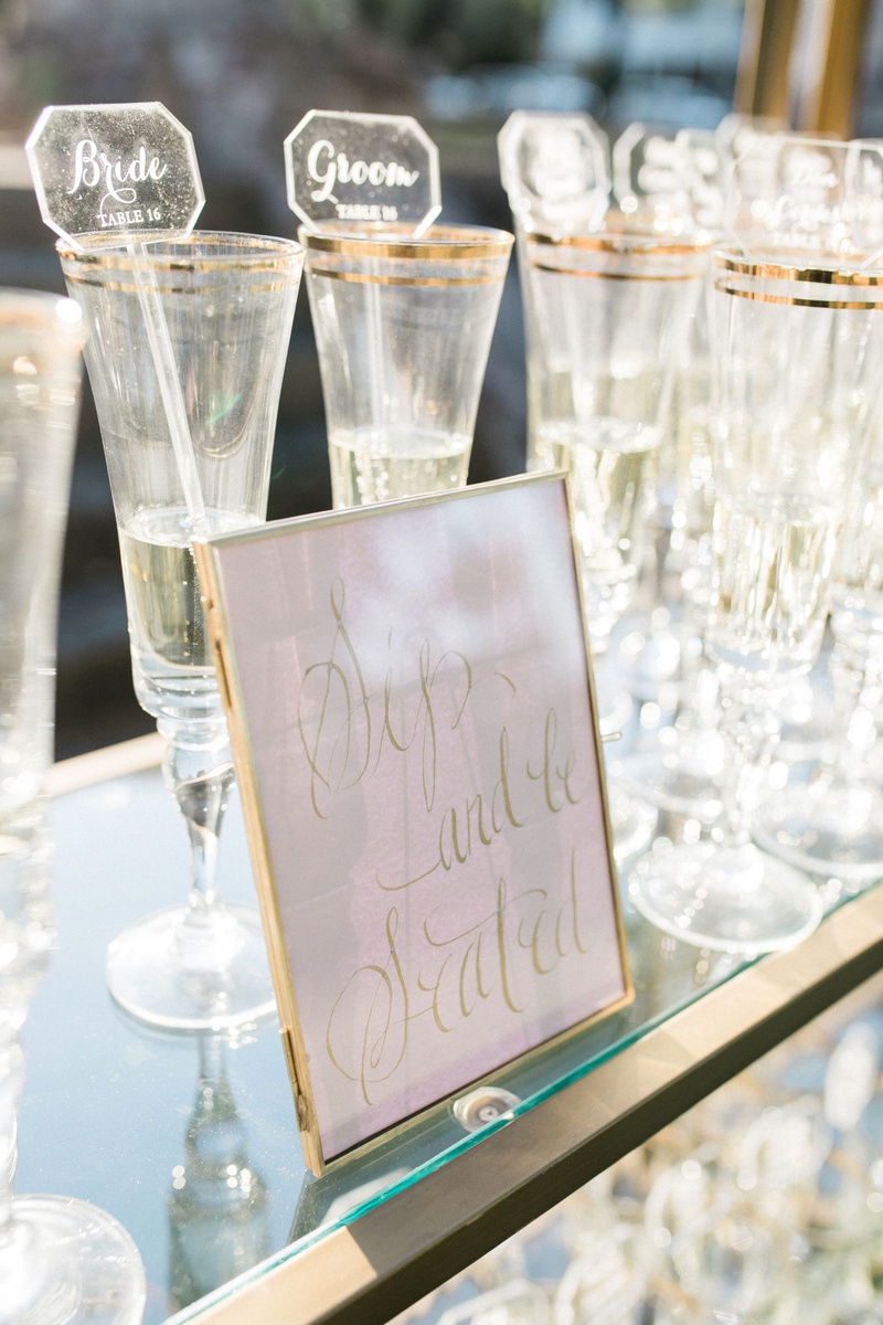 Sip %26 Be Seated Champagne
Photography: Vitor Lindo Photo + Video
Read More:
http://www.insideweddings.com/weddings/soft-romantic-spring-destination-wedding-in-south-carolina/1285/ wedding escort cards on acrylic drink stirrers champagne glasses on gold glass bookcase bookshelf