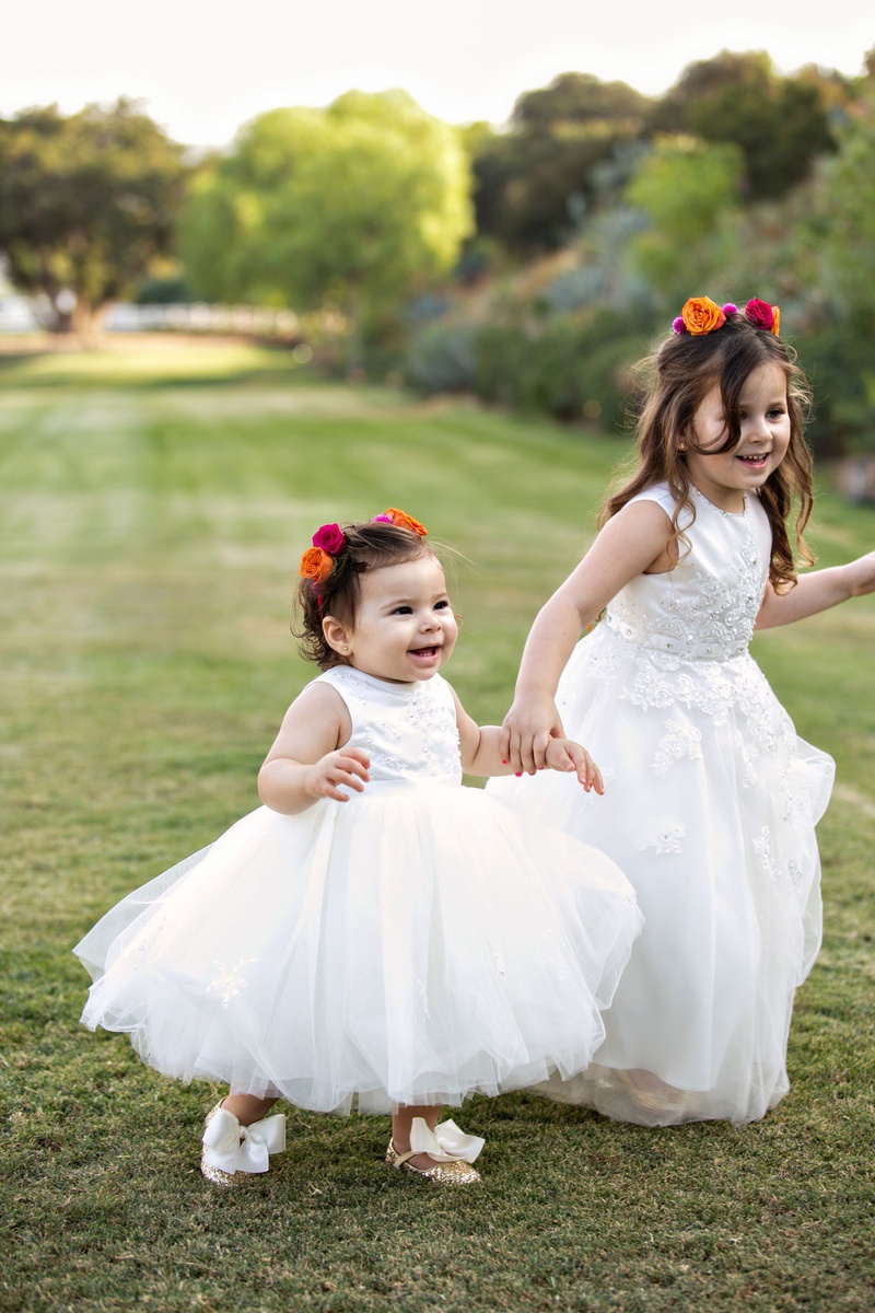 Flower Girls with Roses in Hair
Photography: Laurie Bailey Photography
Read More:
http://www.insideweddings.com/weddings/outdoor-jewish-ceremony-reception-with-colorful-bohemian-decor/1330/ cute flower girls holding hands outdoor grass glitter shoes with bows ball gown pink orange roses