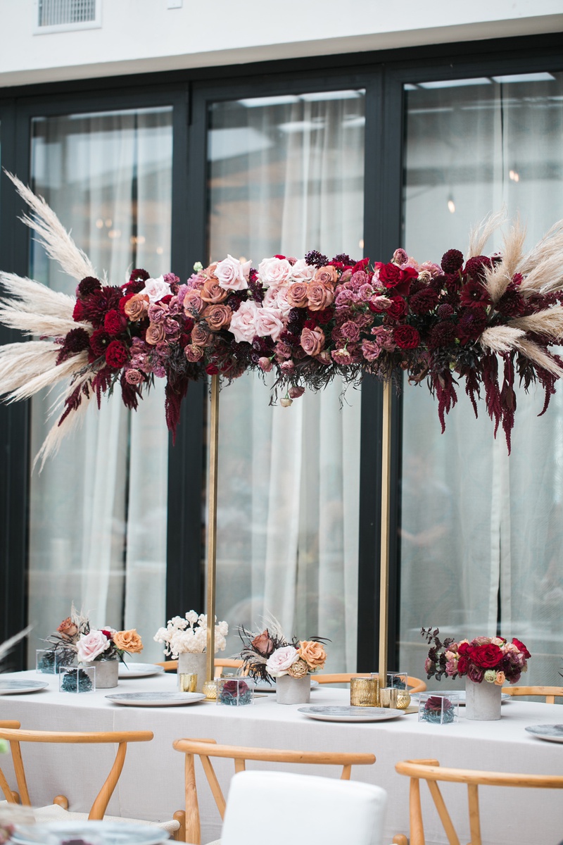 Arrangement of Moody Florals
Photography: Jessica Claire Photography
Read More:
http://www.insideweddings.com/weddings/unique-chic-bridal-shower-with-dark-and-moody-color-scheme/1335/ burgundy, red, mauve roses with pampas grass on gold stand