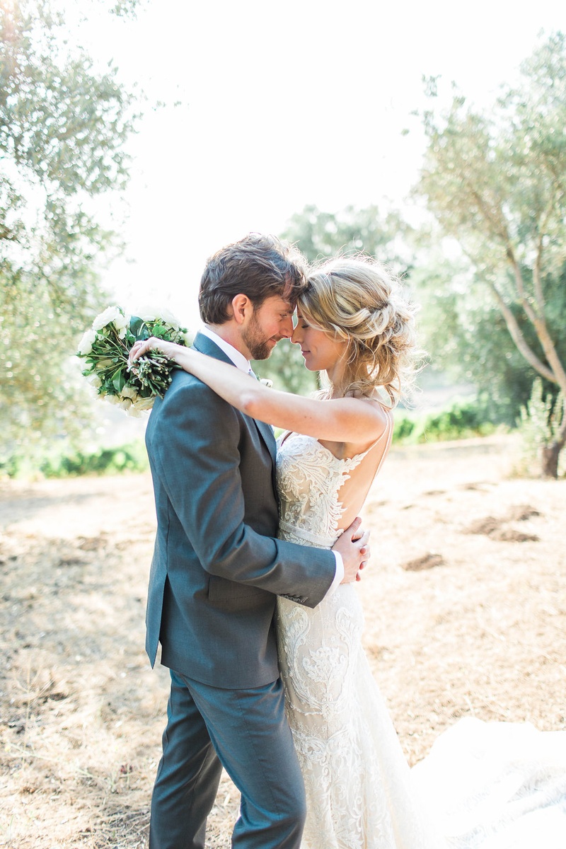 Sweet Portrait of Rustic Wedding Couple
Photography: Katie Shuler Photography
Read More:
http://www.insideweddings.com/weddings/rustic-chic-outdoor-wedding-at-a-winery-in-northern-california/945/ Bride closes eyes and puts arms around groom while holding bouquet berta wedding dress grey suit