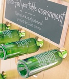 Wine Bottle Table Assignments
Photography: Clane Gessel Photography
Read More:
http://www.insideweddings.com/weddings/rustic-inspired-summer-wedding-at-a-vineyard-in-northern-california/651/ Wedding reception table assignment written on green wine bottles held by a wood board