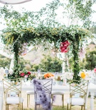 Suspended Greenery Centerpiece
Photography: Scott Clark Photo
Read More:
http://www.insideweddings.com/weddings/whimsical-outdoor-destination-wedding-at-a-ranch-in-california/1378/ wedding reception white table gold chairs purple chair cover overhead greenery centerpiece pink