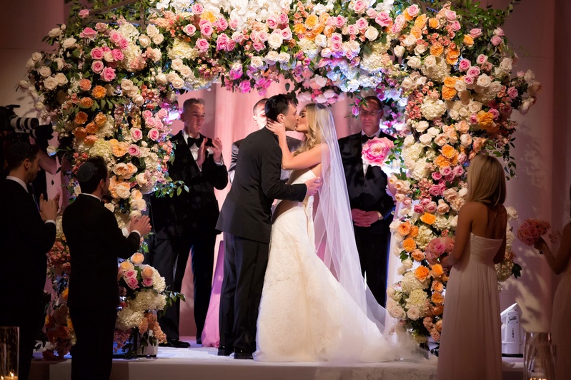 Couple Kisses Under Lush Floral Arch
Photography: Muñoz Photography
Read More:
http://www.insideweddings.com/weddings/colorful-jewish-ceremony-ballroom-reception-at-the-breakers/818/ Bride in strapless Vera Wang wedding dress kissing groom under flower chuppah at Jewish wedding