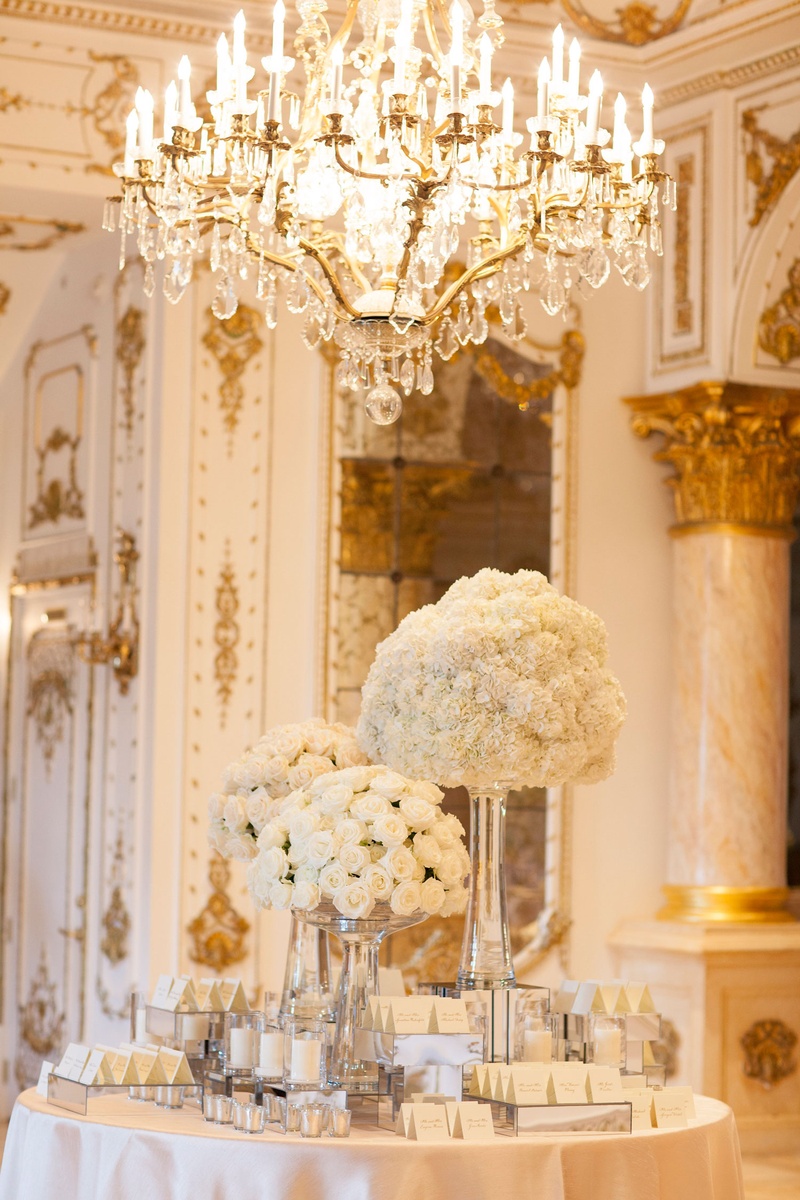 Escort Card Table Under Chandelier
Photography: Nancy Cohn Photography
Read More:
http://www.insideweddings.com/weddings/destination-wedding-with-white-gold-color-palette-in-palm-beach/1028/ Wedding reception round table with white rose bouquet arrangements tall ceilings chandelier white