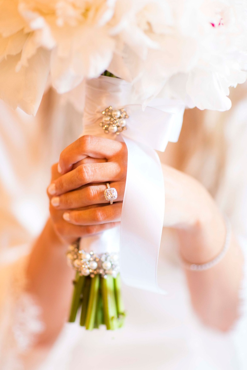 Bride Clutching Bouquet with Ring
Photography: Nancy Cohn Photography
Read More:
http://www.insideweddings.com/weddings/destination-wedding-with-white-gold-color-palette-in-palm-beach/1028/ Halo engagement ring neutral manicure clutching bouquet white ribbon and pearl pins