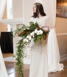 Bride with Cascading Bouquet with Greenery
Photography: Blue Rose Photography
Read More:
http://www.insideweddings.com/weddings/urban-chic-styled-wedding-shoot-with-unique-copper-accents/785/ a bride with a headpiece stands with a large cascading bouquet of white flowers and foliage