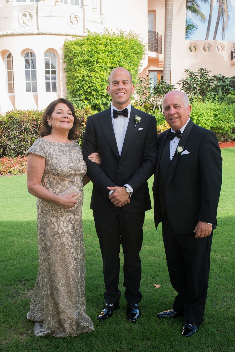 Groom with Mother %26 Father on Lawn
Photography: Nancy Cohn Photography
Read More:
http://www.insideweddings.com/weddings/destination-wedding-with-white-gold-color-palette-in-palm-beach/1028/ Mother of groom in short sleeve gown with father of bride in tuxedo groom in bow tie