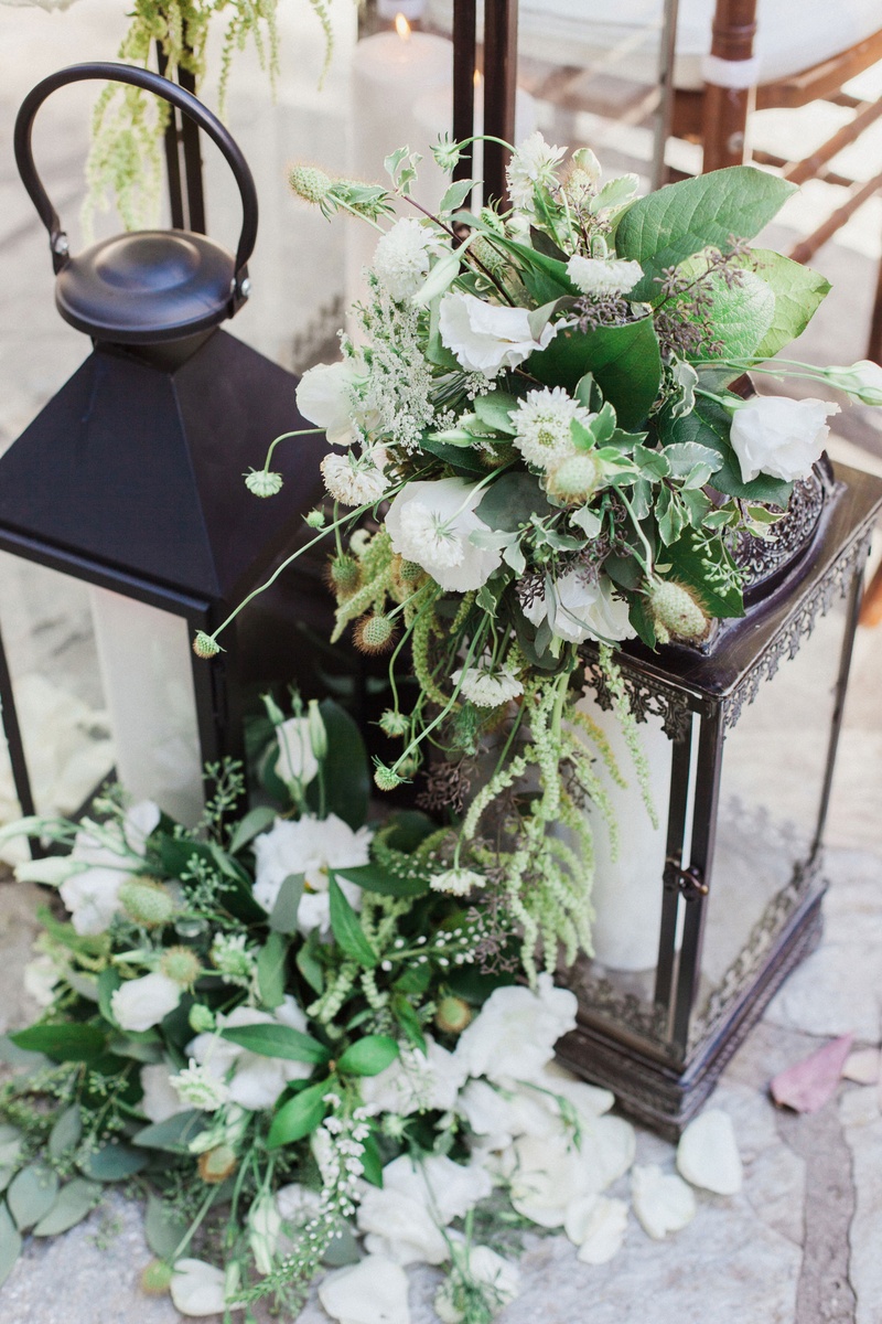 Lanterns with Verdant Florals at Ceremony
Photography: This Modern Romance
Read More:
http://www.insideweddings.com/weddings/rustic-chic-wedding-with-wooden-accents-and-verdant-details/861/ black lanterns at front of ceremony with white flowers and greenery