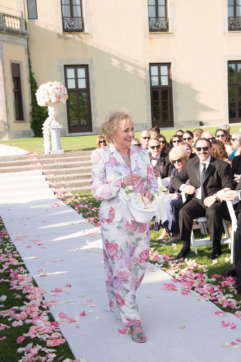 Grandma as Flower Girl
Photography: Brett Matthews Photography
Read More:
http://www.insideweddings.com/weddings/regal-outdoor-ceremony-ballroom-reception-at-oheka-castle-in-ny/821/ Grandma walking down white aisle runner at Oheka Castle in flower print dress with matching jacket