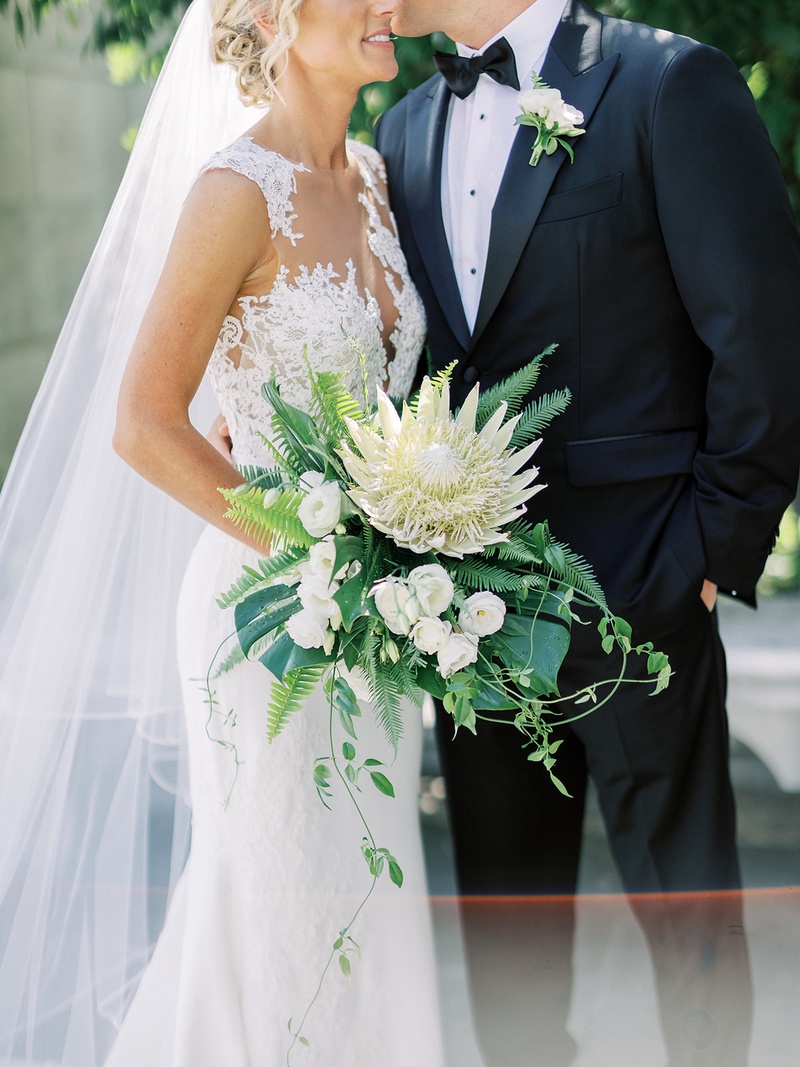 Tropical King Protea Bouquet
Photography: Lauren Gabrielle Photography
Read More:
http://www.insideweddings.com/weddings/summer-real-wedding-featuring-tropical-decor-at-an-art-museum/1328/ bride holding large bouquet with ivory king protea flower tropical greenery illusion wedding dress