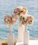 Flower Arrangements on Pillars
Photography: Brian Leahy Photography
Read More:
http://www.insideweddings.com/weddings/alfresco-ceremony-with-sweeping-ocean-views-tented-reception/1112/ Three white pillars with vases full of white and pink flowers at wedding ceremony