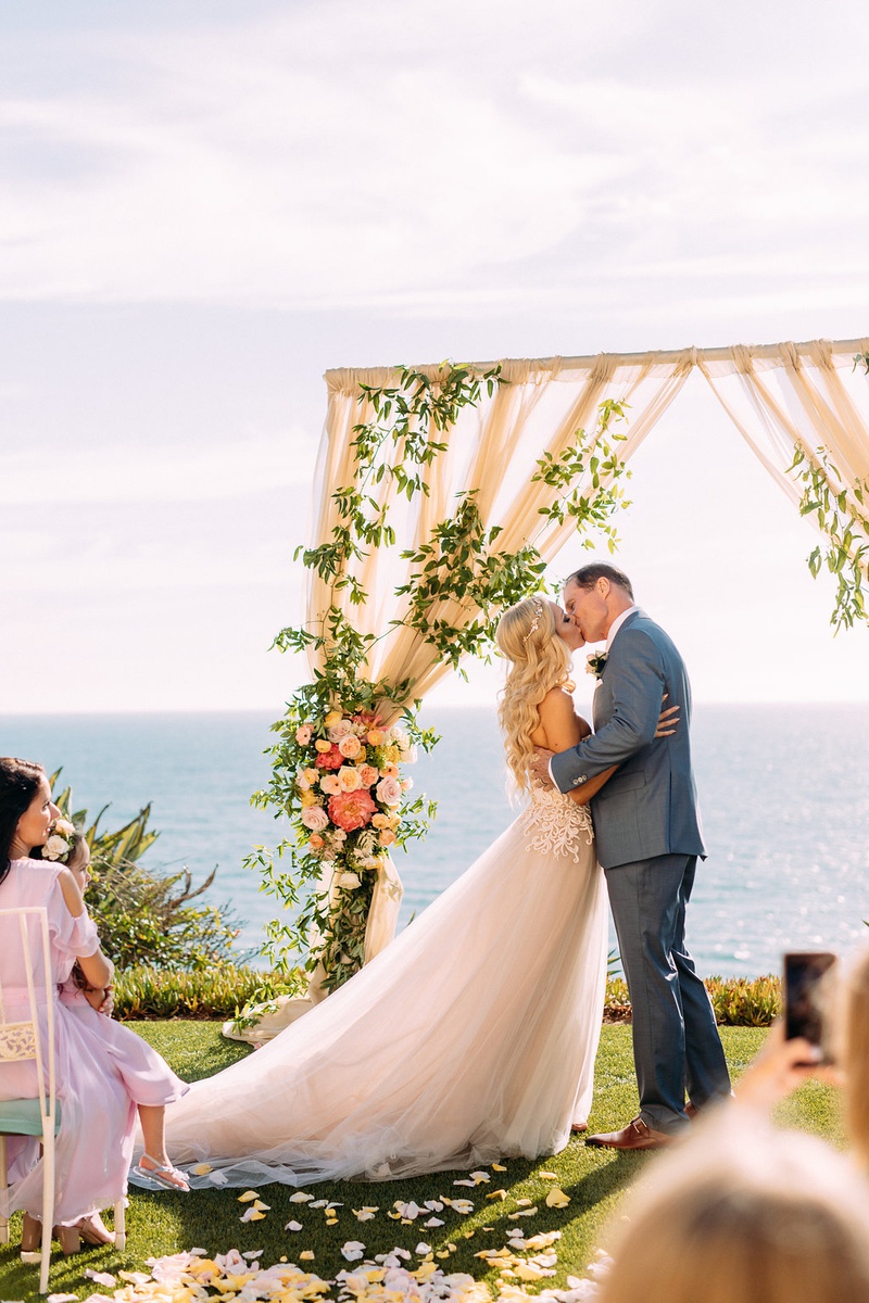Ocean-View Kiss as Husband and Wife
Photography: Ashley Paige Photography
Read More:
http://www.insideweddings.com/weddings/romantic-ocean-view-ceremony-charming-reception-in-california/1337/ bride in custom trish peng wedding dress groom grey suit kiss ocean view ceremony pastel decor