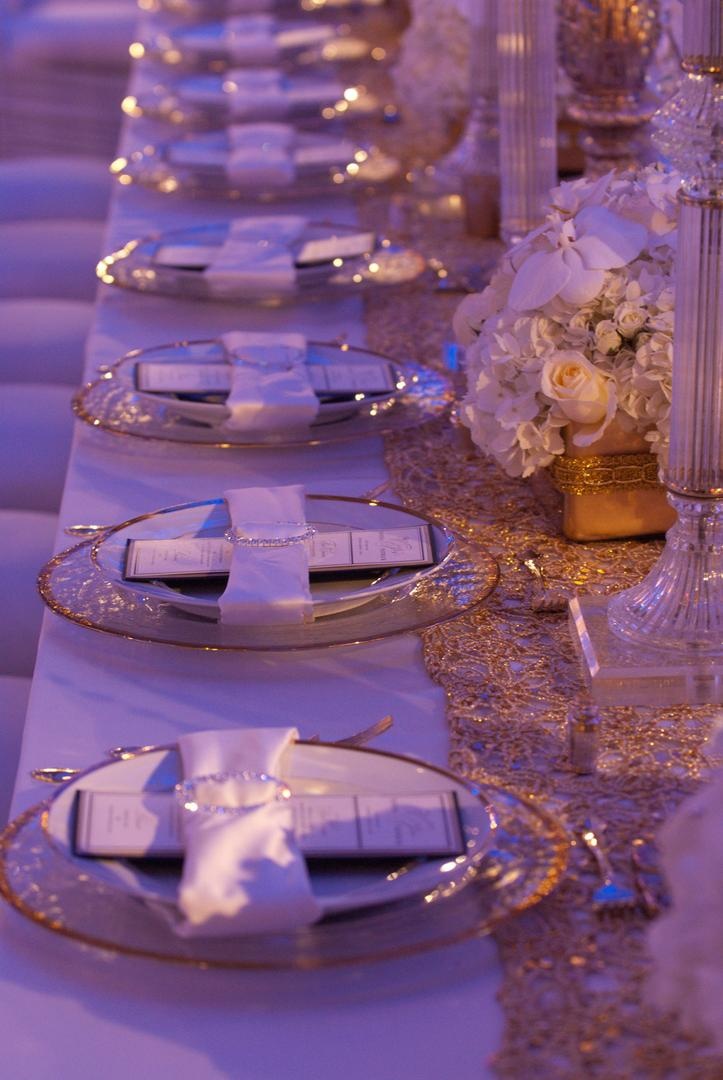 Place Settings
Photography: Josh Lynn Photography
Read More:
http://www.insideweddings.com/weddings/purple-white-gold-new-jersey-celebration/339/ Wedding reception place setting with gold-rimmed dinnerware and satin white napkin with crystal ring