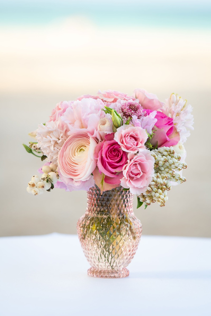 Pretty Pink Small Centerpiece in Vase
Photography: Suzanne Delawar Studios
Read More:
http://www.insideweddings.com/weddings/intimate-oceanfront-wedding-with-romantic-red-pink-white-palette/1235/ wedding reception centerpiece pink rose ranunculus flowers in light pink crystal vase beach ocean
