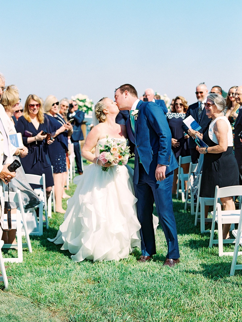 Bride %26 Groom Kiss Mid-Aisle
Photography: Bonnie Sen Photography
Read More:
http://www.insideweddings.com/weddings/outdoor-ceremony-tented-reception-by-a-tranquil-river-in-maryland/1088/ Wedding outdoors grass lawn white chairs for guests groom in blue suit bride in strapless dress kiss