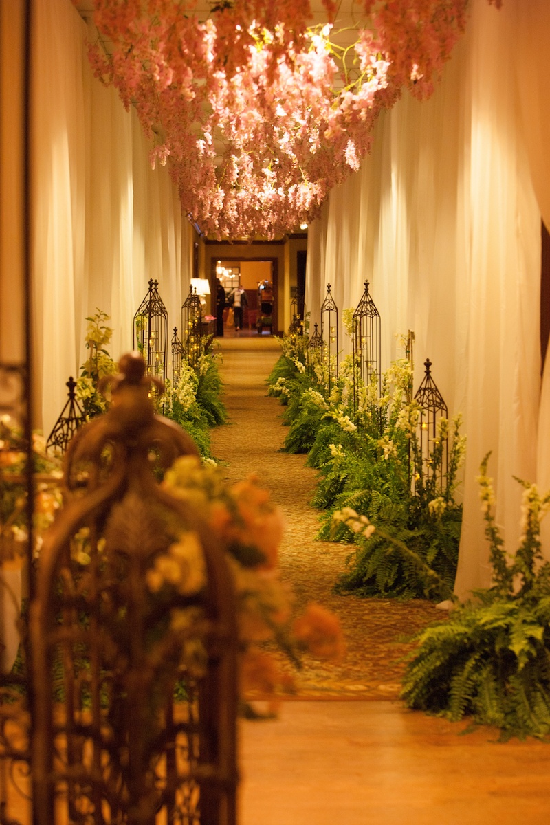 Nature-Inspired Hallway to Ballroom
Photography: Michael Carr Photography
Read More:
http://www.insideweddings.com/weddings/traditional-church-ceremony-forest-inspired-reception-in-houston/695/ Wedding reception hallway entrance with pink flowers from ceiling