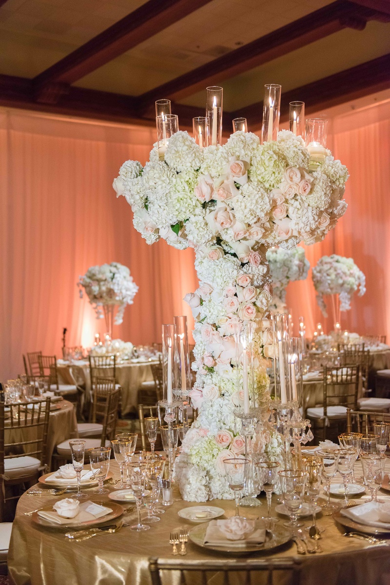 Candelabrum-Inspired Centerpiece
Photography: The Yodsukars
Read More:
http://www.insideweddings.com/weddings/glam-10th-wedding-anniversary-party-vow-renewal-in-california/917/ Flower sculpture centerpiece with candelabra details gold linens tall flower arrangement