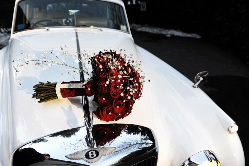 Bride's Bouquet
Photography: Josh Lynn Photography
Read More:
http://www.insideweddings.com/weddings/purple-white-gold-new-jersey-celebration/339/ Bride's bouquet of red roses and crystals on the hood of a classic white Bentley