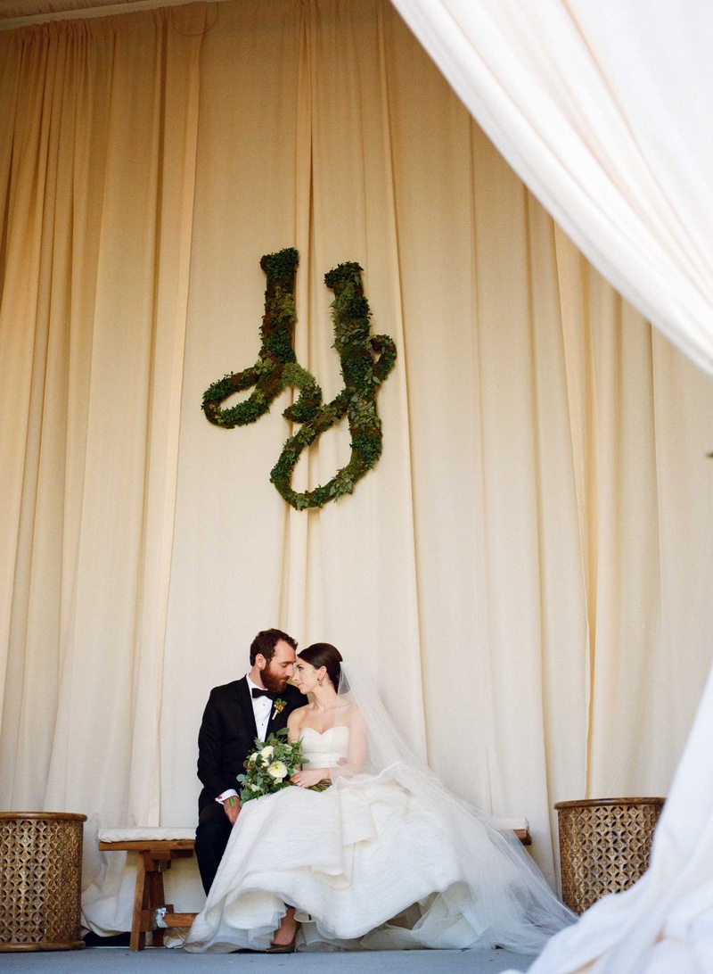 Couple Under Wedding Monogram
Photography: Gabe Aceves Photography
Read More:
http://www.insideweddings.com/weddings/warm-cozy-wedding-at-unique-warehouse-venue-in-washington-dc/902/ Bride and groom at rustic wedding greenery sculpture in monogram wall art on drapery