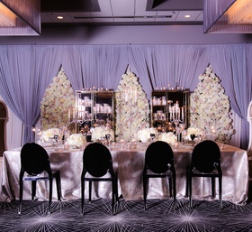 Grand Head Table at Styled Shoot
Photography: Gold Grid Studios
Read More:
http://www.insideweddings.com/weddings/celebratory-wedding-shoot-with-elegant-romantic-decor-in-chicago/728/ Wedding reception with long head table in silver tablecloth, black ghost chairs, floral panels
