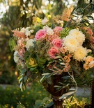 Blush, White, and Green Floral Arrangement
Photography: Paul Barnett Photographer
Read More:
http://www.insideweddings.com/weddings/bohemian-outdoor-garden-wedding-ceremony-rustic-reception/830/ a cluster of pink white and green flowers and leaves in gold vase outside couples ceremony space