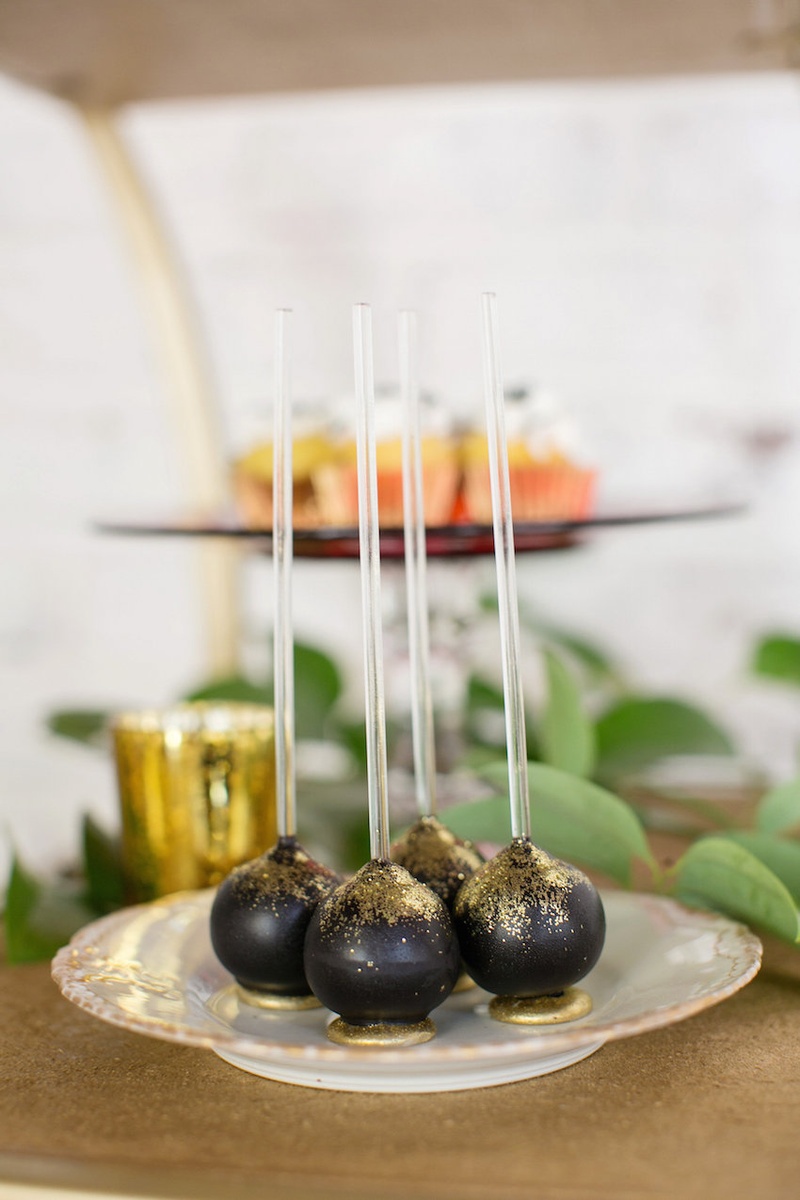 Gold-Dusted Chocolate Cake Pops Photography: Kristina Lee Photography Read More: http://www.insideweddings.com/weddings/inspirational-wedding-shoot-with-black-red-white-geometric-decor/700/ Wedding reception dessert table with chocolate cake pops sprinkled with gold on a china plate