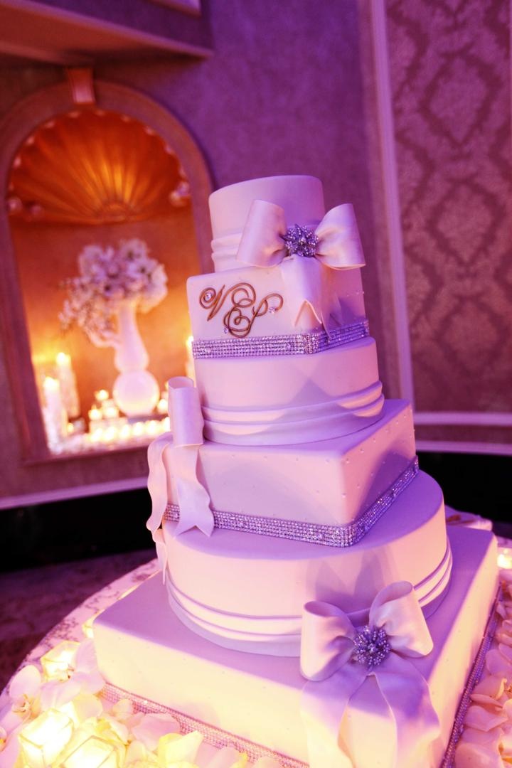 Wedding Cake
Photography: Josh Lynn Photography
Read More:
http://www.insideweddings.com/weddings/purple-white-gold-new-jersey-celebration/339/ White wedding cake with crystals and fondant ribbons surrounded by candles