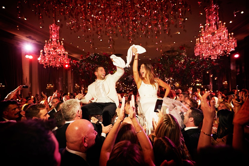 Celebratory Hora at Luxury Chicago Wedding
Photography: KingenSmith
Read More:
http://www.insideweddings.com/weddings/luxurious-wedding-featuring-sentimental-butterfly-decor-in-chicago/1348/ wedding reception bride and groom on chairs with guests at reception chandelier red lighting