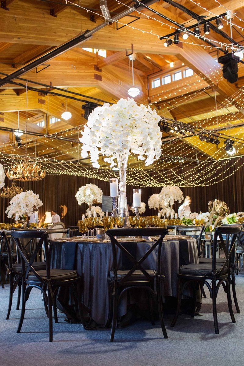 Tall Orchid Centerpiece at Barn Venue
Photography: Perez Photography
Read More:
http://www.insideweddings.com/weddings/incredible-tented-ceremony-barn-reception-at-ranch-in-aspen/860/ Aspen Colorado wedding reception in wood barn with dark linens chairs and tall white orchid flowers