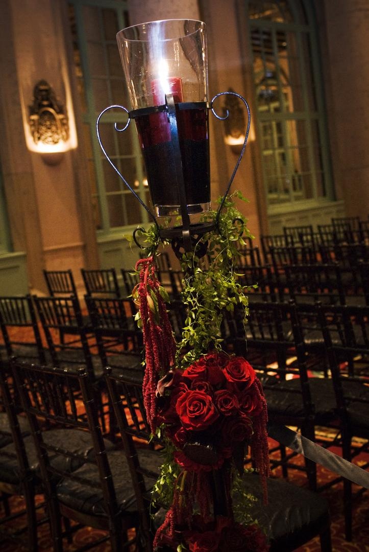 Ceremony Décor
Photography: Barnet Photography
Read More:
http://www.insideweddings.com/weddings/ashley-reeves-and-brandon-saller/261/ Wrought iron stand decorated with greenery and red roses topped with red pillar candle